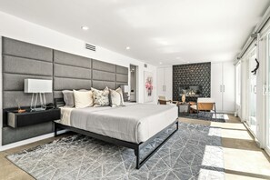 Une chambre à coucher moderne avec un grand lit, une table de chevet, une télévision et un panneau décoratif mural.
