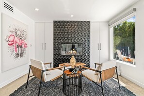 A modern dining area with a geometric wall panel, a fireplace, and a large window.