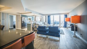 A modern living room with a dining area, a kitchen, and a balcony with large windows.