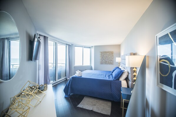 A modern hotel room with a large bed, a desk, and a view of the city. - Gorgeous updated condo, 2nd floor, amazing views + Free Attraction Tickets! (Myrtle Beach)