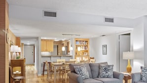 Ein modernes Wohnzimmer mit einem grauen Sofa, einem Holztisch und einem Essbereich mit Tisch und Stühlen.
