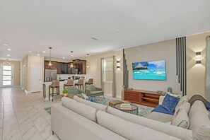 A modern living room with a sofa, coffee table, and a TV mounted on the wall.