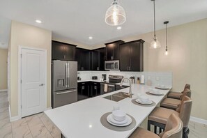 A modern kitchen with dark cabinets, stainless steel appliances, and a central island with seating.