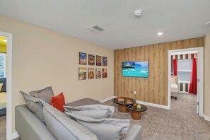 A living room with a sofa, a coffee table, and a flat-screen TV mounted on the wall.