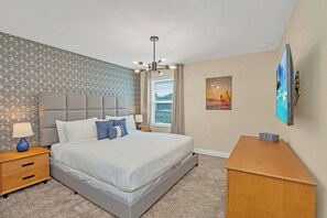 Et hotelværelse med en stor seng, et natbord med en lampe, et skrivebord og et billede på væggen.