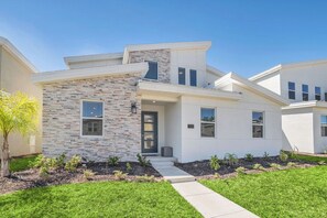 A modern two-story house with a stone facade, a front door, and a small porch.