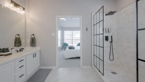 A modern bathroom with a white vanity, a large mirror, and a shower area.