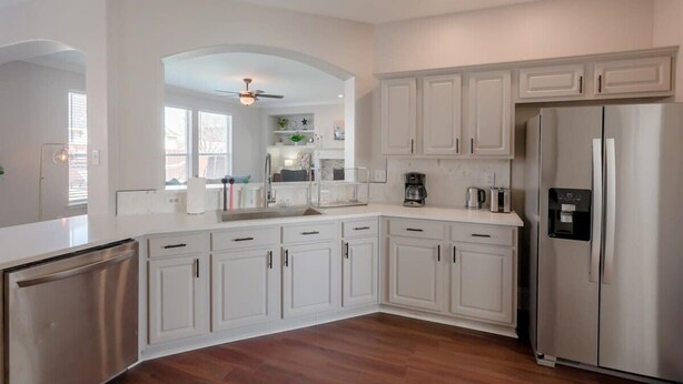 A modern kitchen with white cabinetry, stainless steel appliances, and a central island.