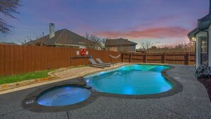 A backyard with a swimming pool, a hot tub, and a wooden fence.