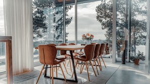 A modern dining area with a large table and chairs, large windows with a view of trees and a cityscape. - Most Luxurious 5-bed Villa in Boo Stockholm (Värmdö)