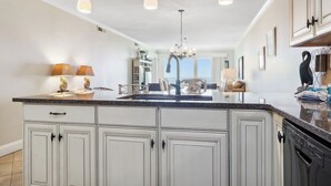 A kitchen with a large island, white cabinetry, pendant lighting, and a view of the ocean. - Shorewood 403- Oceanfront 4th Floor Condo (Hilton Head Island)