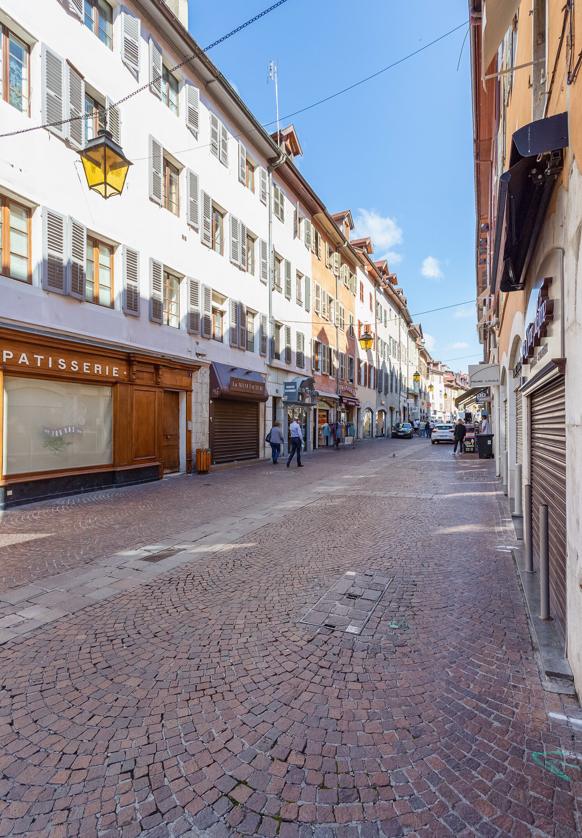 A cobblestone street with buildings on either side, including a bakery and a closed shop.