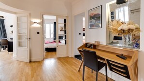 A modern bedroom with a wooden desk, a large mirror, and a bed with a pink blanket.