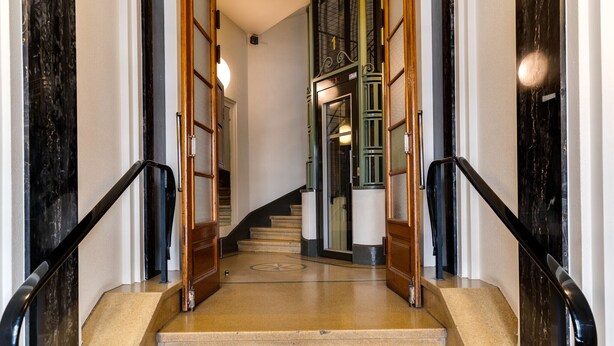 A staircase with a marble floor leading to a door with a number sign.