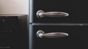 A black refrigerator with chrome handles in a kitchen.