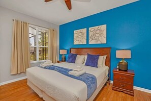 A bedroom with a large bed, beige curtains, a blue wall, and two wall art pieces. - Stunning Home w Private Pool & Spa, Free Waterpark (Kissimmee)