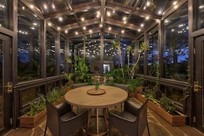 Relax in this serene outdoor space with a round table, comfortable seating, and lush greenery.