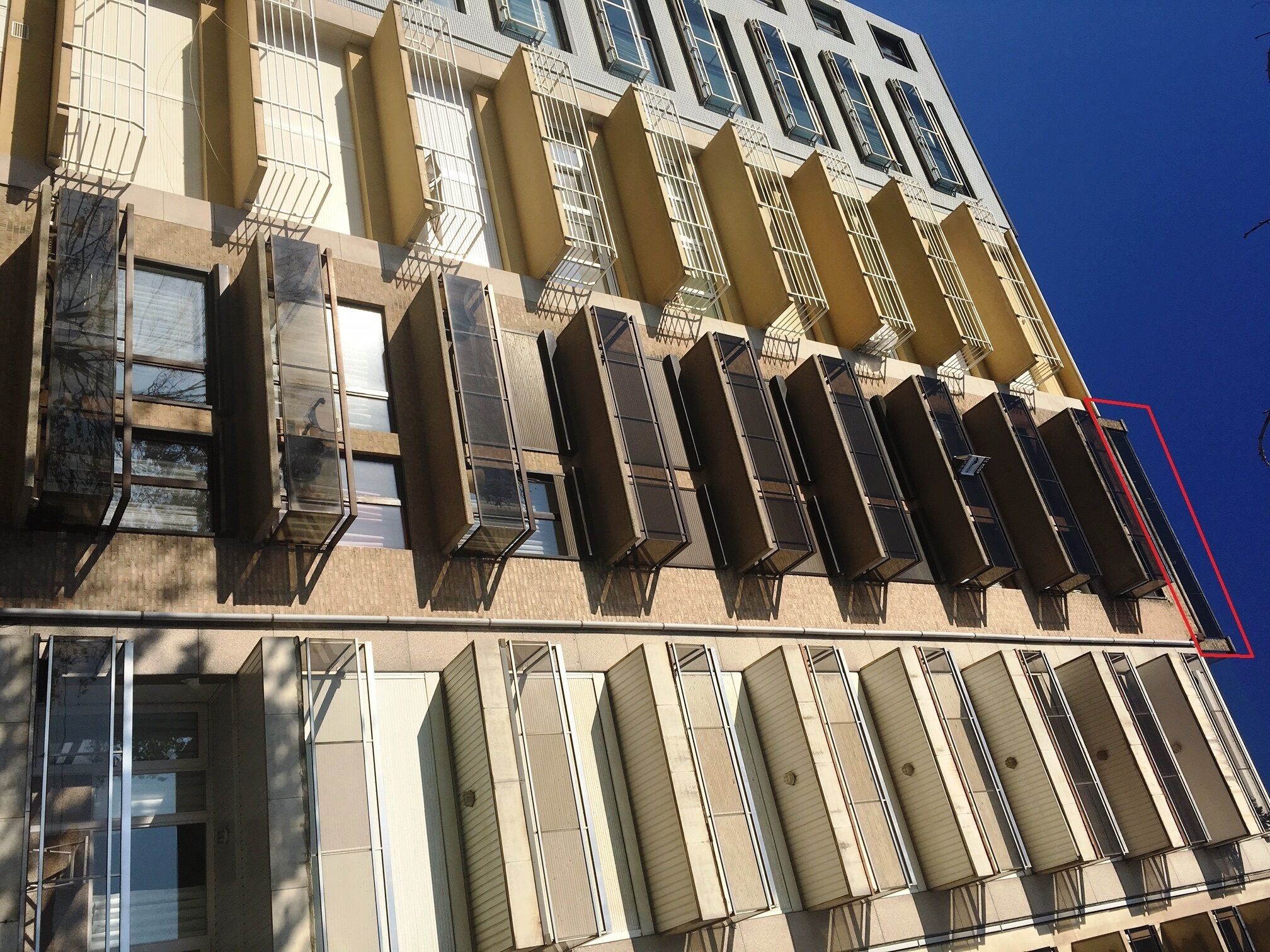 Een gebouw met meerdere verdiepingen, voorzien van een rij balkons en ramen.