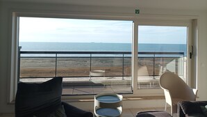 Une pièce dotée d’une grande porte-fenêtre coulissante donnant sur un balcon avec vue sur la mer.
