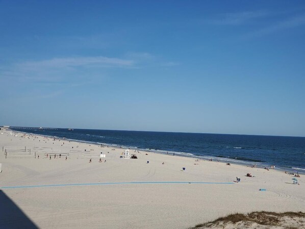 A wide sandy beach with a clear blue sky and calm sea.