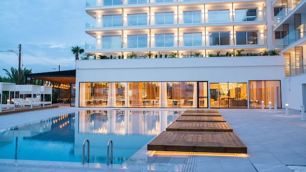 Et moderne hotel med swimmingpool, flere etager og en godt oplyst indgang.