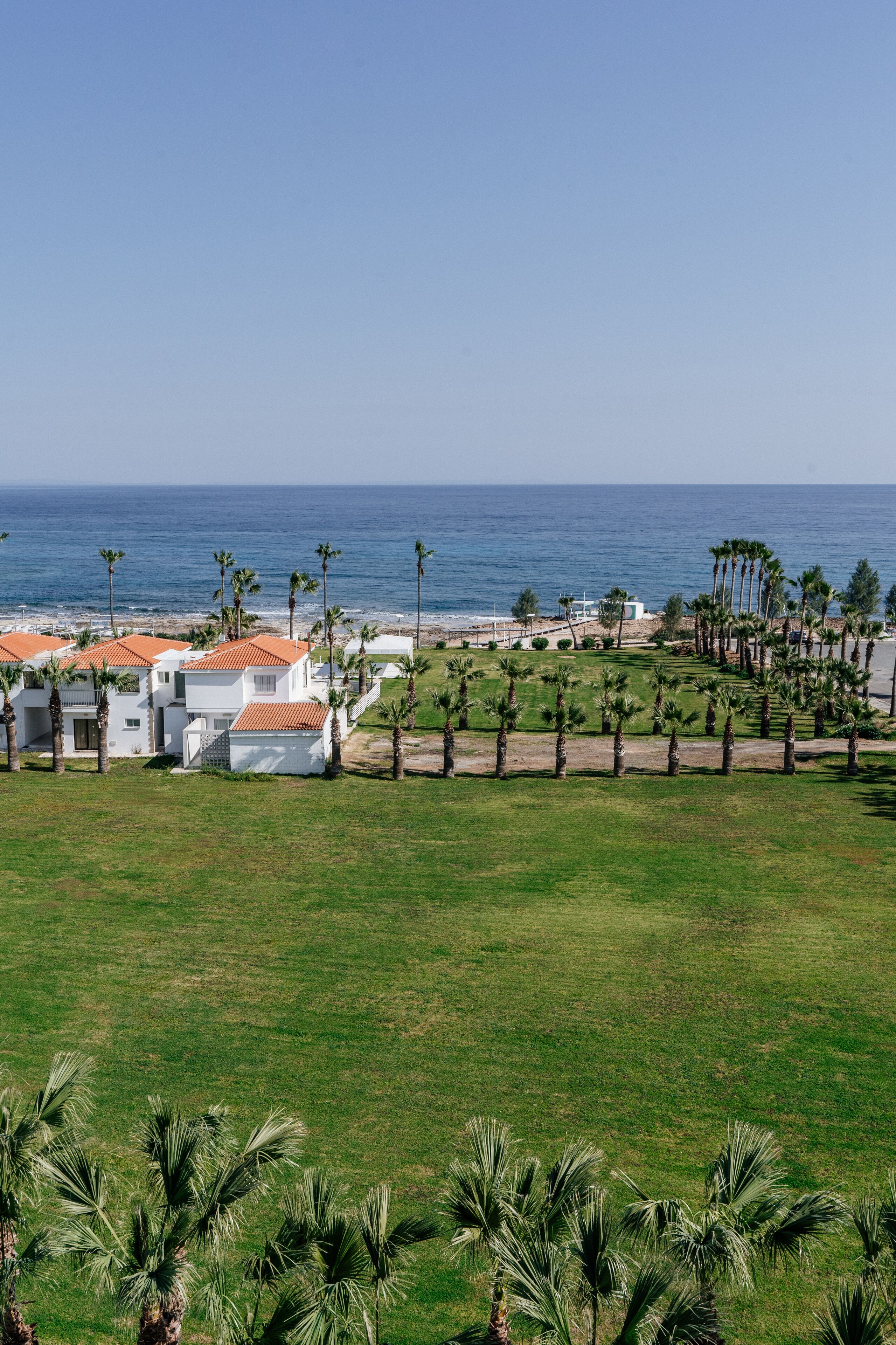 A coastal resort with white buildings, palm trees, and a view of the ocean.