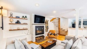 Un salon moderne doté d’une cheminée, d’un téléviseur et d’un escalier menant à un autre niveau.