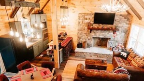 A cozy, rustic interior with a stone fireplace, wooden furniture, and a dining area with red placemats. - Luxury Vacation Mountain Home (Pickens)