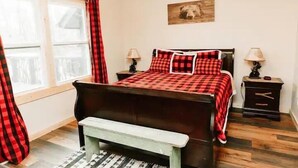 A bedroom with a bed, bedside tables, a bench, a window with curtains, and a wall-mounted picture. - Luxury Vacation Mountain Home (Pickens)