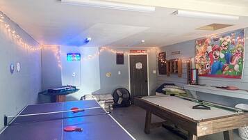 Une pièce équipée d’une table de ping-pong, d’un billard et d’un espace de jeux avec un panneau indiquant « Zone sans Grinch ».