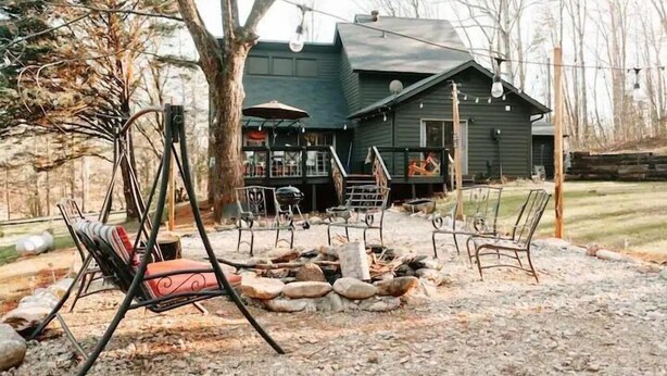 A rustic outdoor seating area with a swing chair, a fire pit, and a covered patio. - Luxury Vacation Mountain Home (Pickens)