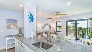 A modern kitchen with a large island, a built-in dishwasher, and a view to the outdoor patio. - Direct Oceanfront Villa / Heated Pool & Ocean View (Hilton Head Island)