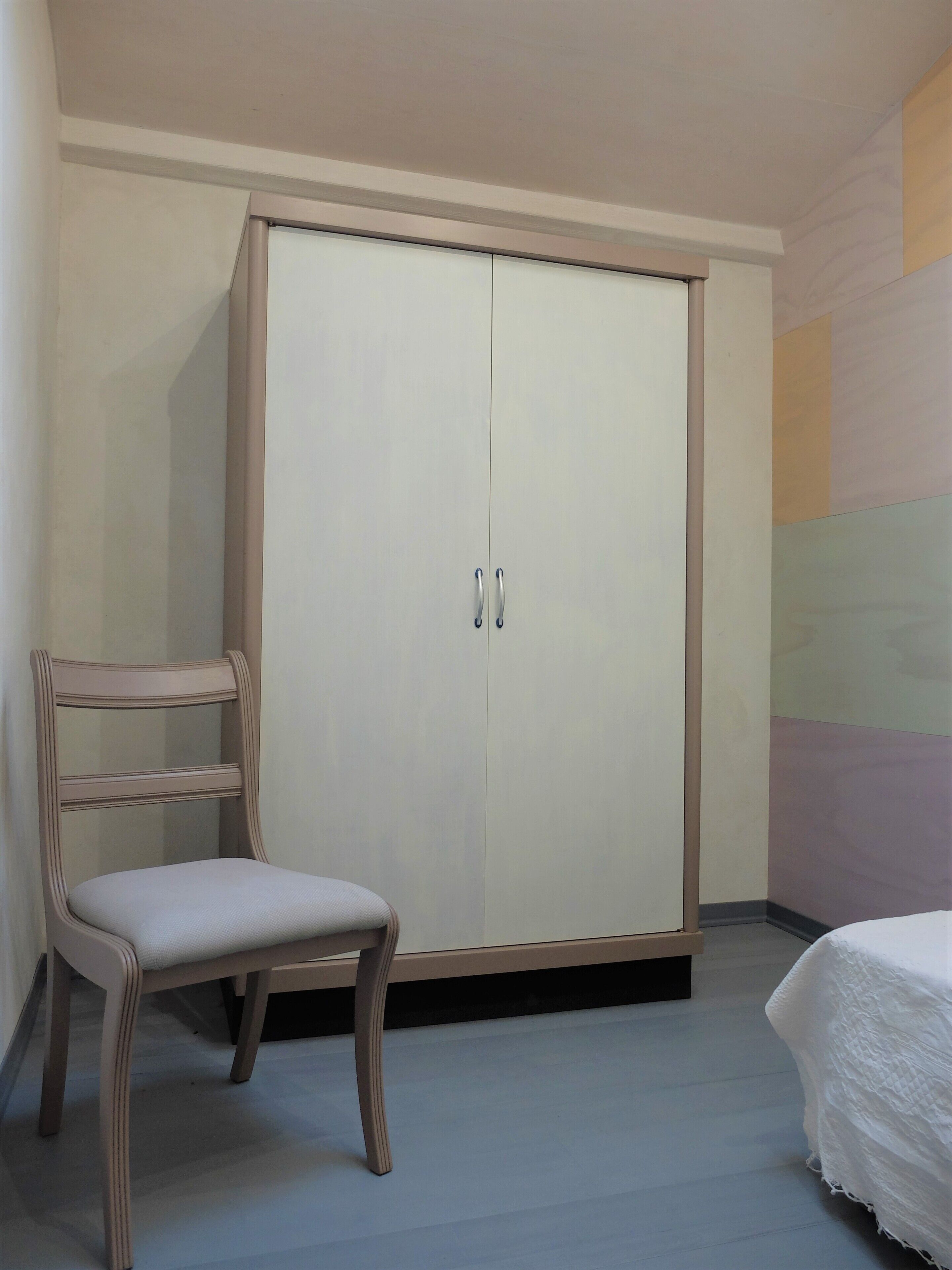 Une chambre à coucher avec une armoire, une chaise et un lit.