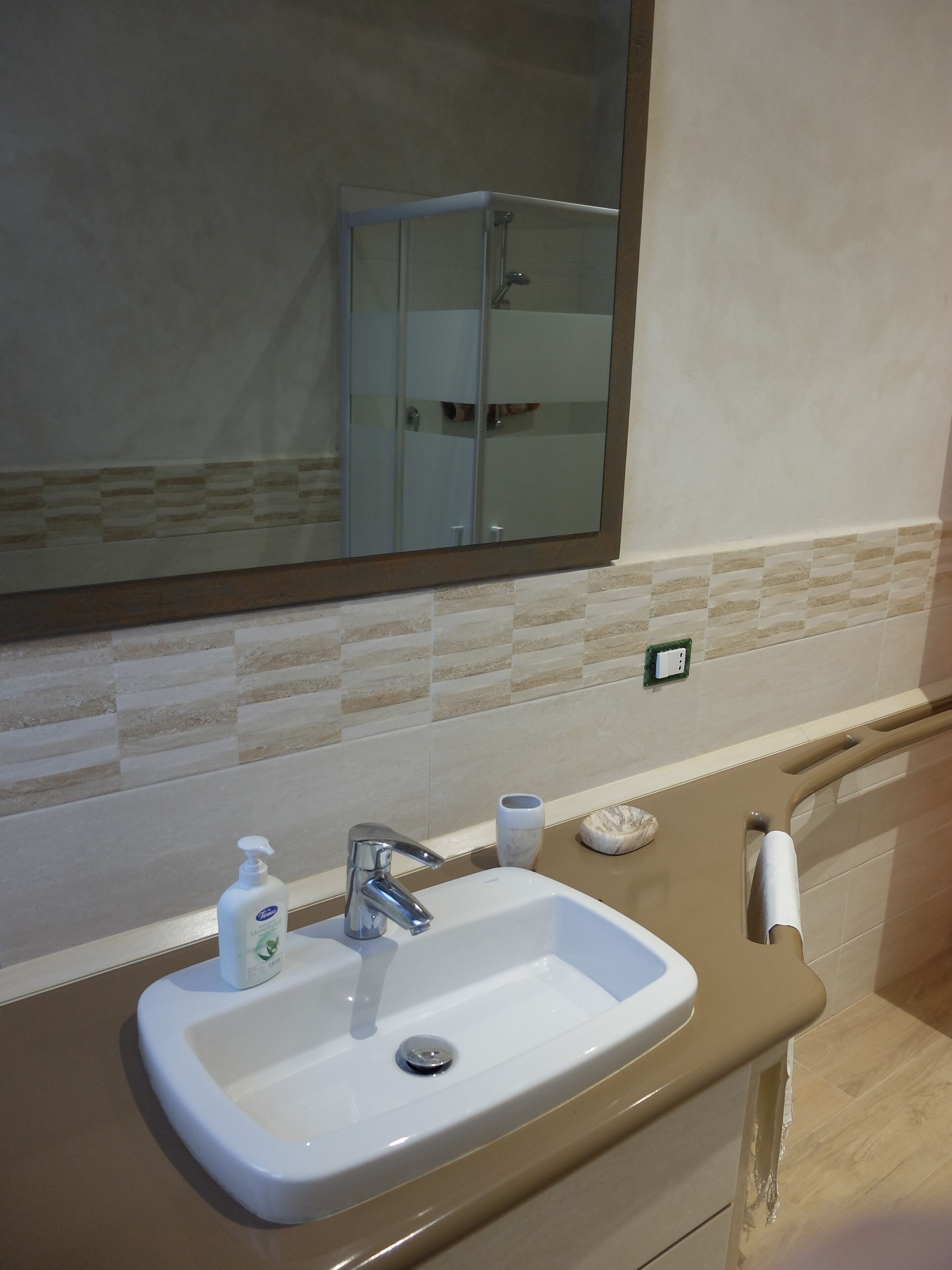 Une salle de bain avec un lavabo blanc, un miroir et une douche.