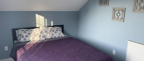 A bedroom with a bed, a window, and wall decorations.