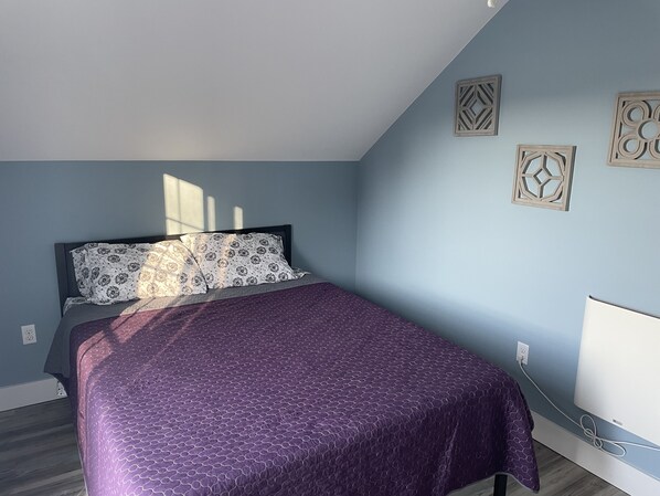 A bedroom with a bed, a window, and wall decorations.