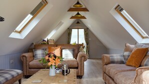 Ein gemütliches Wohnzimmer im Loft-Stil mit hohen Decken und Dachfenstern, ausgestattet mit Ledersofas, einem Holztisch und einer dekorativen Vase.