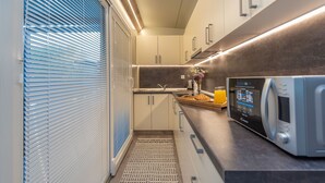 A modern kitchen with a built-in microwave, a sink, and a window with blinds. - Mobile Home Pecten Exclusive 2 (Pakostane)