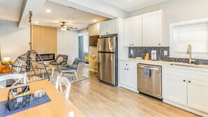 Une cuisine moderne avec des meubles blancs, des appareils en acier inoxydable et un coin repas comprenant une table et des chaises en bois.