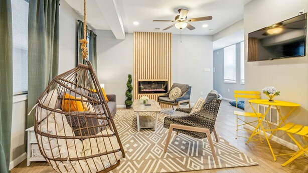 Un salon moderne avec un fauteuil suspendu, un canapé et un téléviseur fixé au mur.
