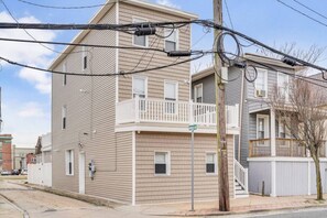 A two-story residential building with a balcony on the second floor, a garage door, and a street sign.
