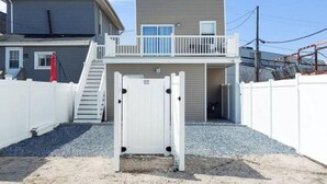 Une maison à deux étages avec un balcon, un portail et une allée gravillonnée.