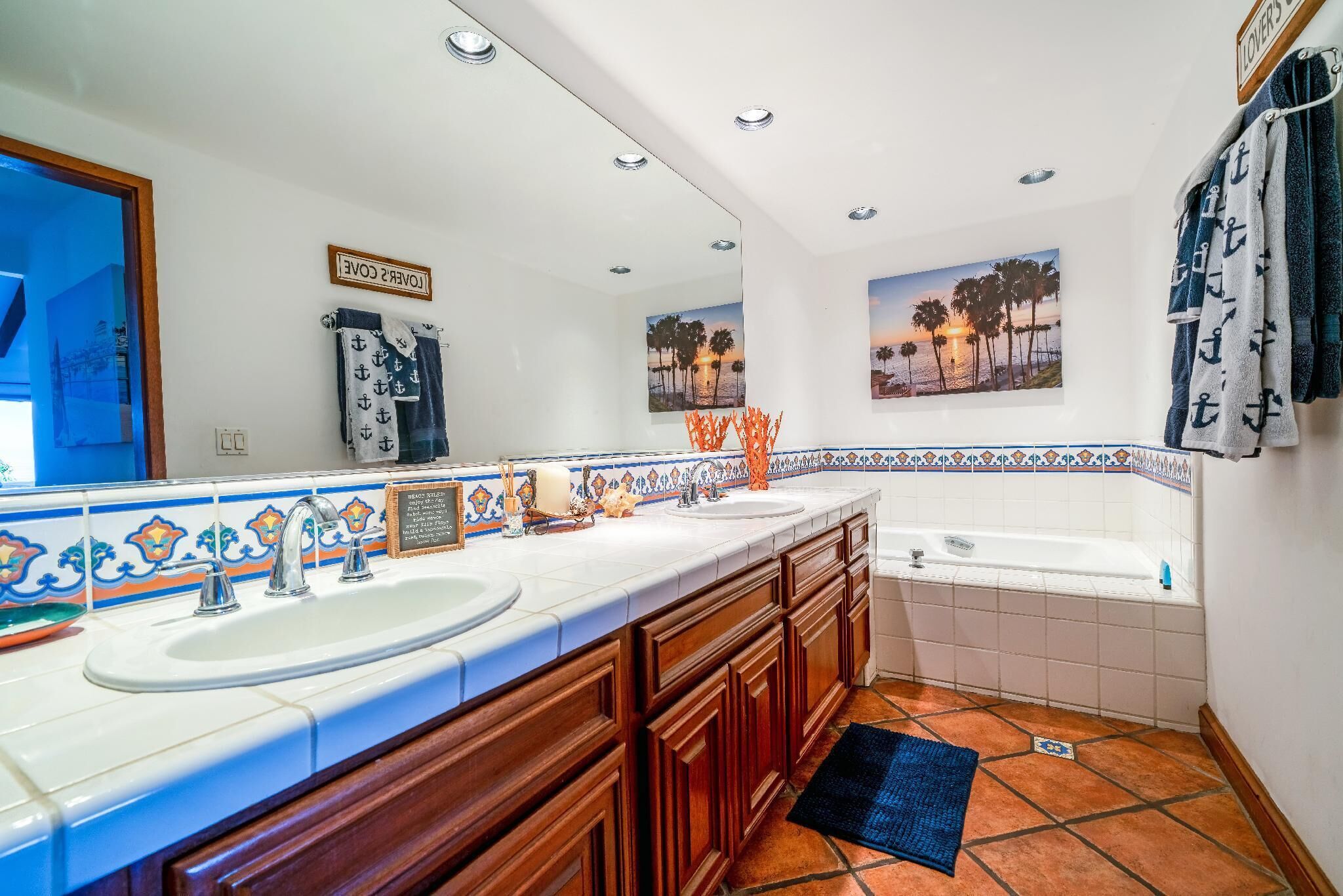 Un baño con un espejo grande, dos lavamanos, una bañera y azulejos decorativos.