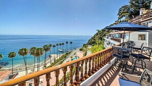 Ein Balkon mit Blick auf den Ozean, Palmen und einen Poolbereich.