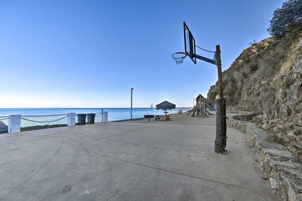 A basketball court with a net, a bench, and a small hut by the sea.