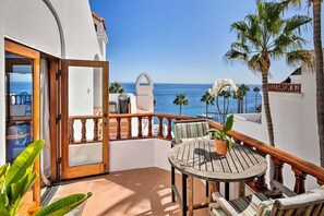 A balcony with a wooden table and chairs, a potted plant, and a view of the ocean. -  Oceanfront Hamilton Cove Penthouse suite with stunning panoramic views! (Avalon)