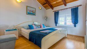 Un dormitorio con cama, mesitas de noche, cortinas en una ventana y un ventilador de techo.