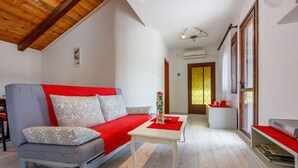 Una sala de estar moderna con un sofá gris, cojines rojos, una mesa de centro blanca y una estantería.