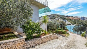 A stone pathway leading to a building with a balcony overlooking a coastal area. - Apartment Seafront Apartments (Kalebova luka)