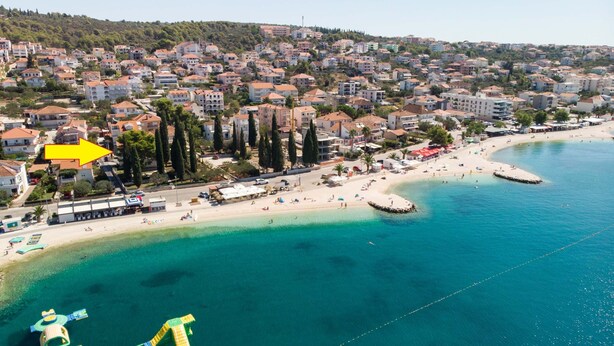 An aerial view of a coastal town with a beach, residential buildings, and a clear blue sea. - Apartment Cypress (Okrug Gornji)